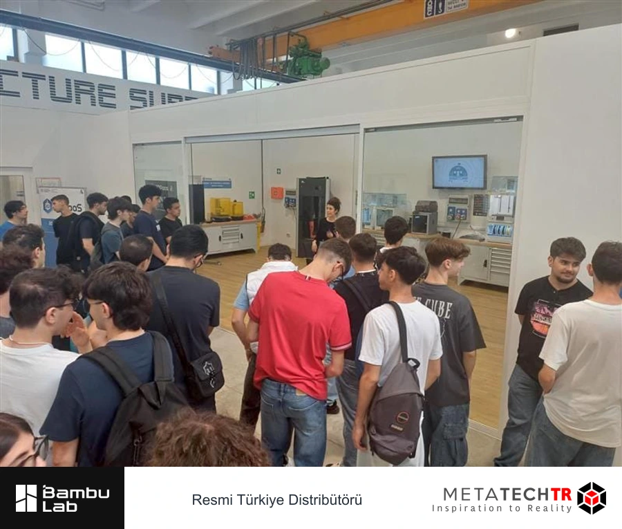 3D yazıcıların önünde toplanmış katılımcılar ve anlatım yapan eğitmen.