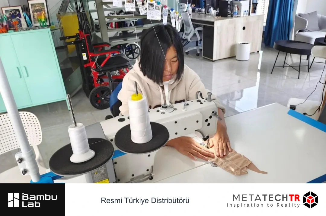 Atölyede dikiş makinesinin başında kumaş üzerinde çalışan Twan.
