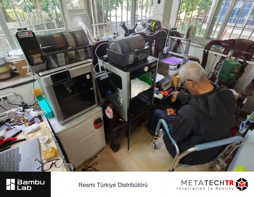 Wu, yan yana duran 3D yazıcıların önünde basılı parçalarla ilgileniyor.