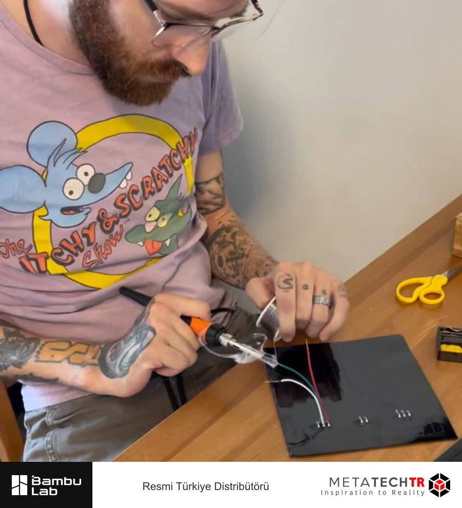 Eric Brunner masadaki bir parça üzerinde kablo ve elektronik bileşenlerle çalışıyor.